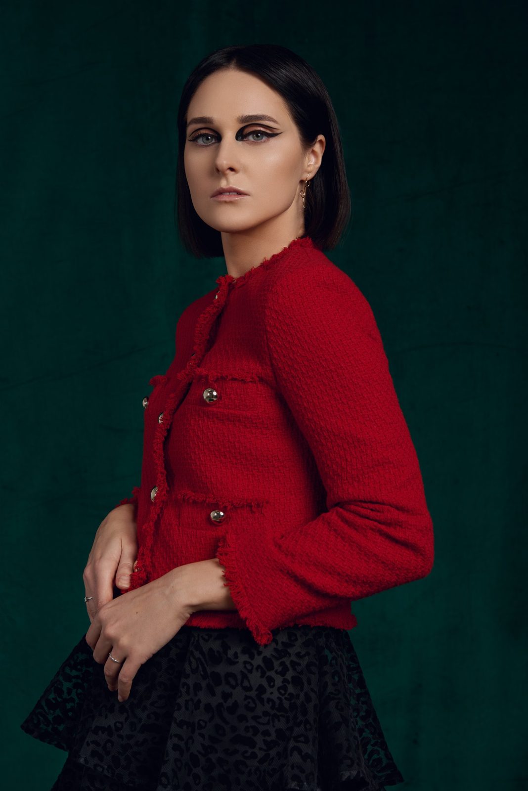 Graphic black cut-crease liner, red tweed jacket on deep green